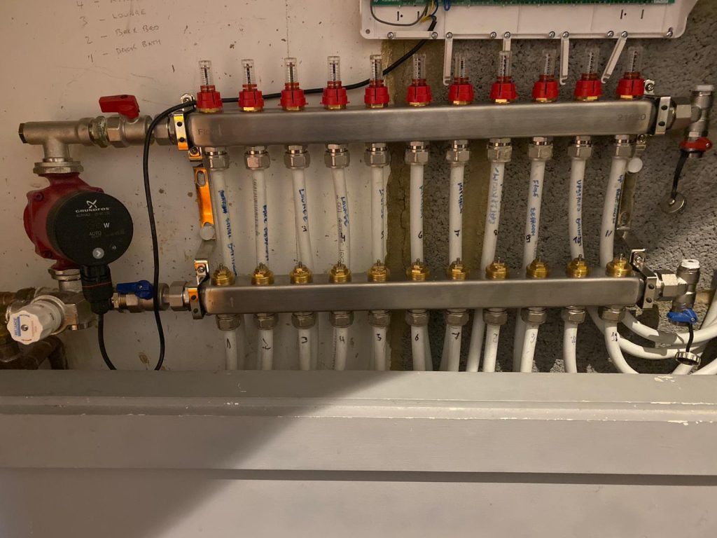 Underfloor heating manifold with labeled PEX pipes and Grundfos pump